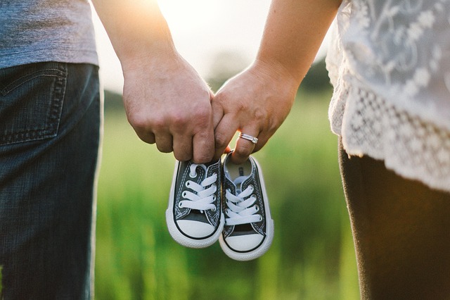 Paar hält kleine Babyschuhe bei Sonnenuntergang.